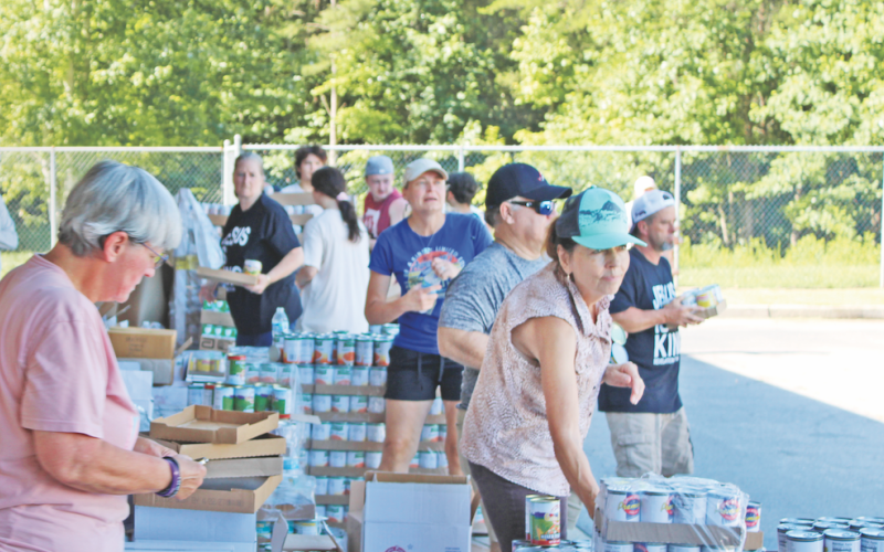 Volunteers organize cans of food and prepare to load them into waiting vehicles at the Unseen Hand Ministry mobile pantry at the parking lot of Blackburn Elementary School in Dahlonega.
